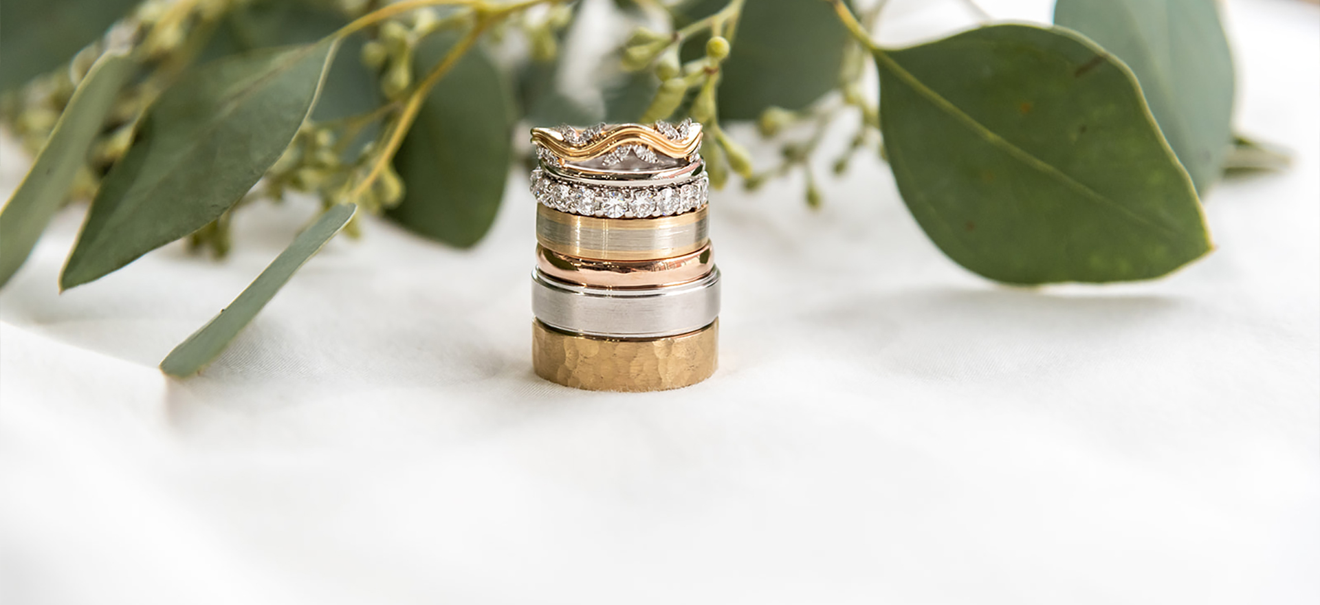 Stacked gold wedding bands with eucalyptus