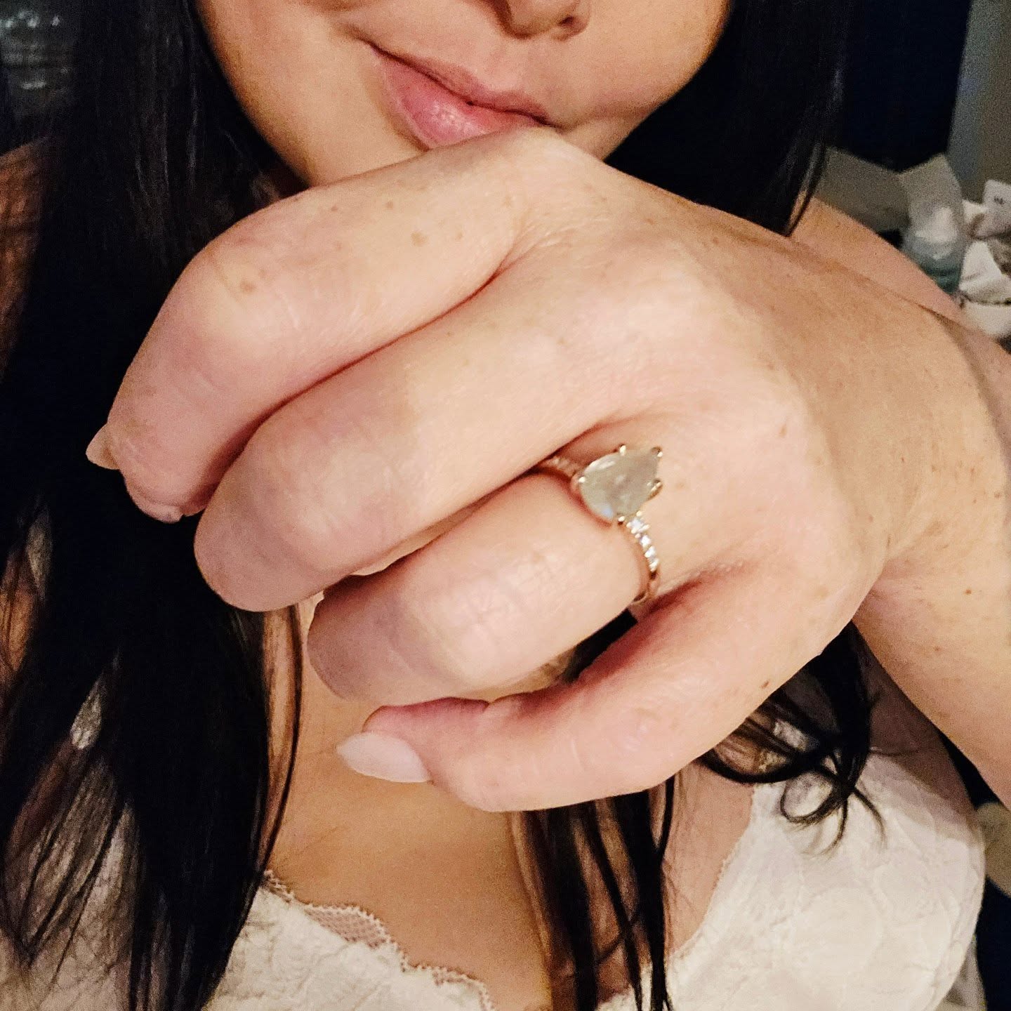 An engagement ring worn on the hand in natural light