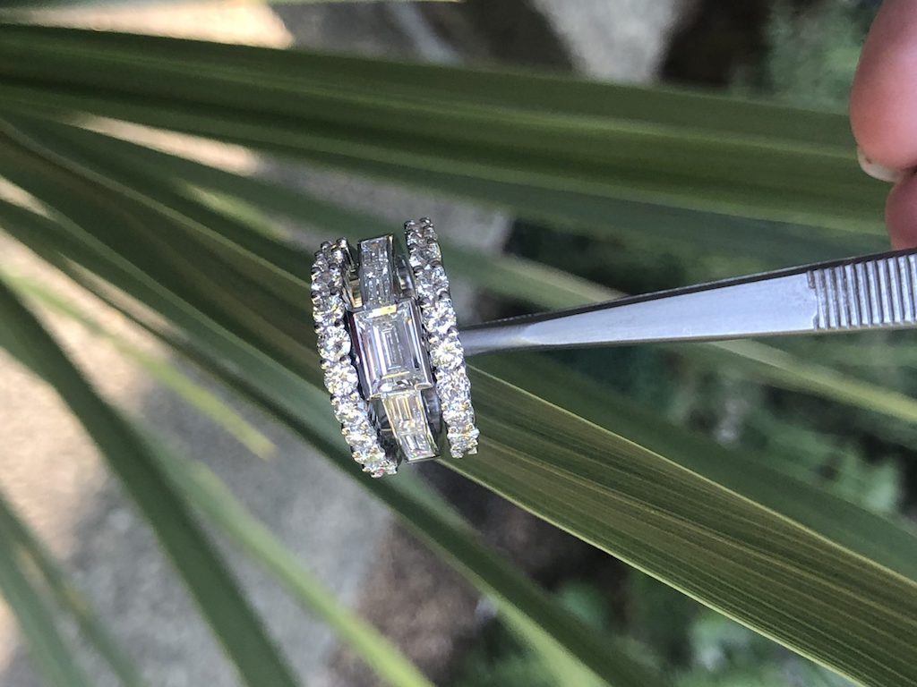 A finished ring held in the jeweller tweezers at the bench