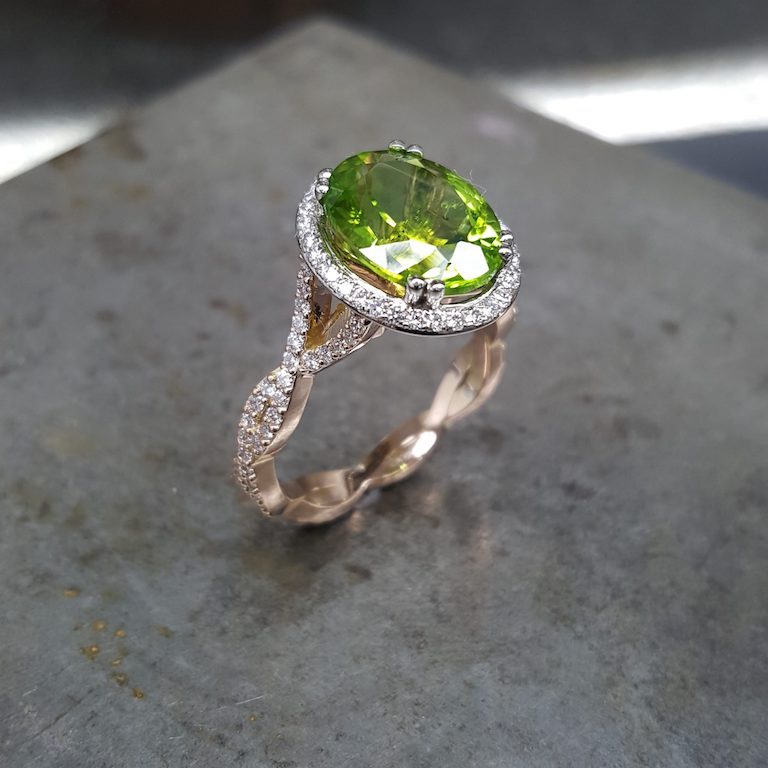 A peridot ring resting on the workbench